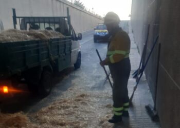Bomberos de Peñaranda limpian el paso inferior de la carretera de Alba para retirar la paja caída de un camión y reabrirlo al tráfico