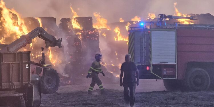 Bomberos y vecinos de Bóveda del Río Almar trabajan en la extinción de un gran incendio en una granja de vacuno de leche